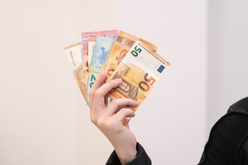 Un homme tenant plusieurs billets en euros. Il exhibe son argent, évoquant des revenus et des investissements. La finance et la monnaie, symboles de richesse et de réussite